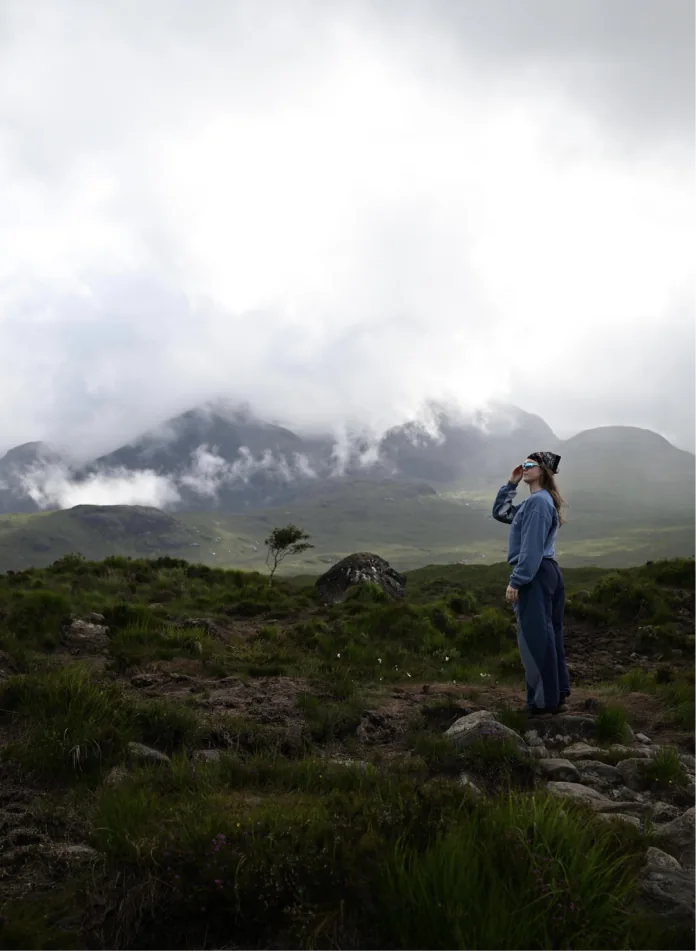 A person looking out at cloud-covered mountains
